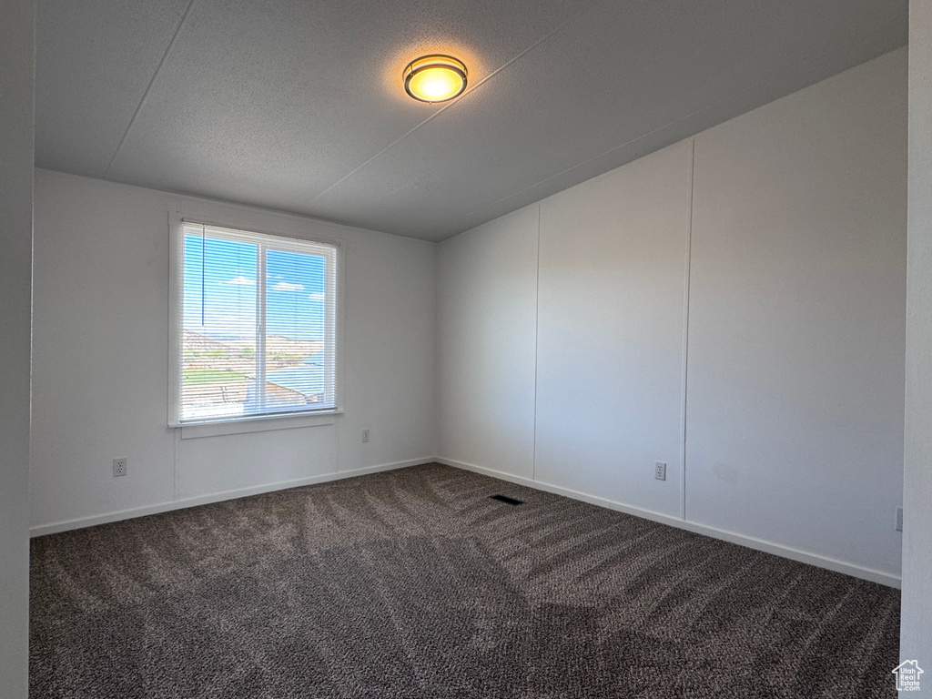 Spare room with dark colored carpet and baseboards
