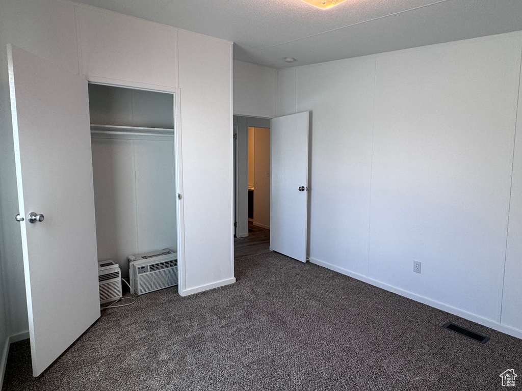 Unfurnished bedroom with dark carpet and a closet