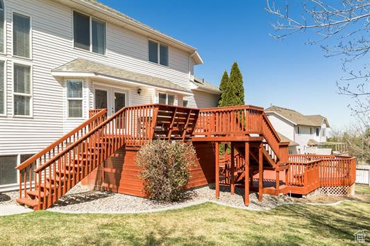 Back of house with stairs, a lawn, and a deck