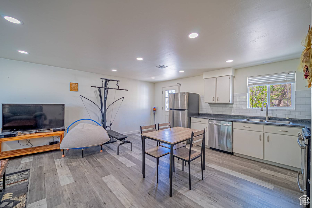 Kitchen with dark countertops, light wood-style floors, a sink, and stainless steel appliances