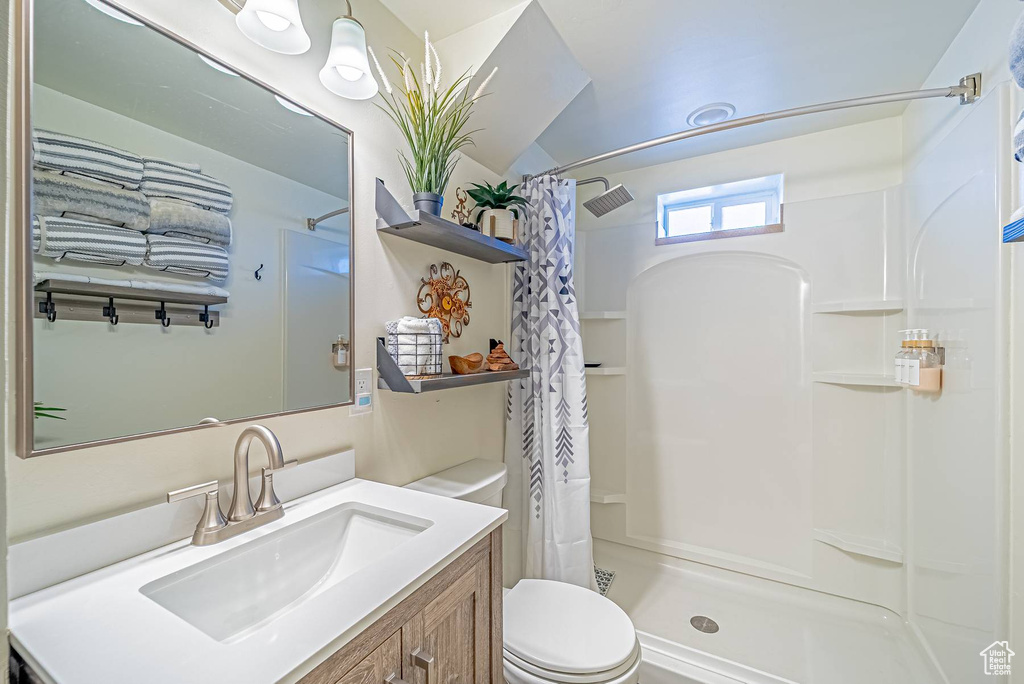 Bathroom featuring toilet, a shower with curtain, and vanity