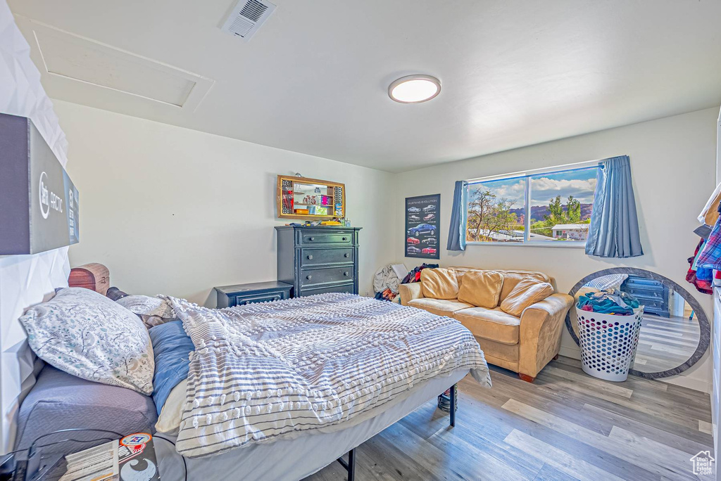Bedroom with wood finished floors, attic access, and visible vents