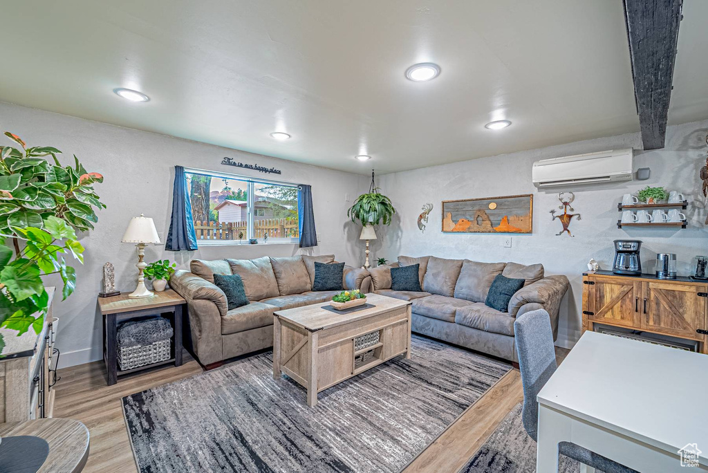 Living room featuring light wood-style flooring, recessed lighting, and a wall unit AC