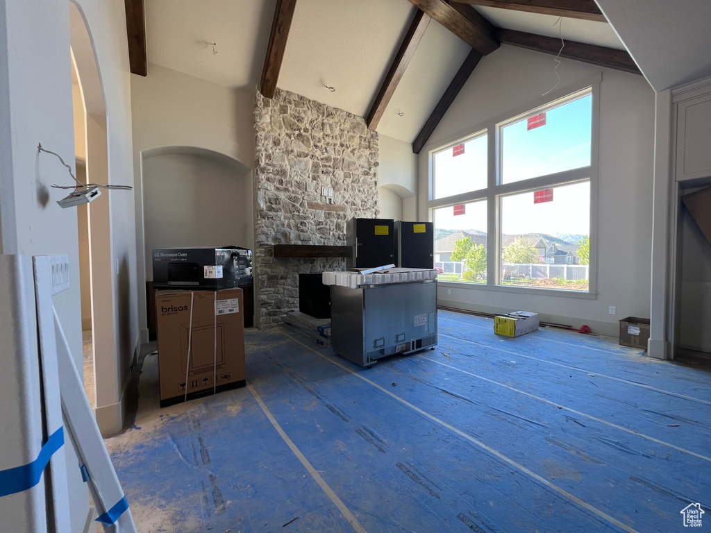 Kitchen with high vaulted ceiling, beamed ceiling, and a fireplace