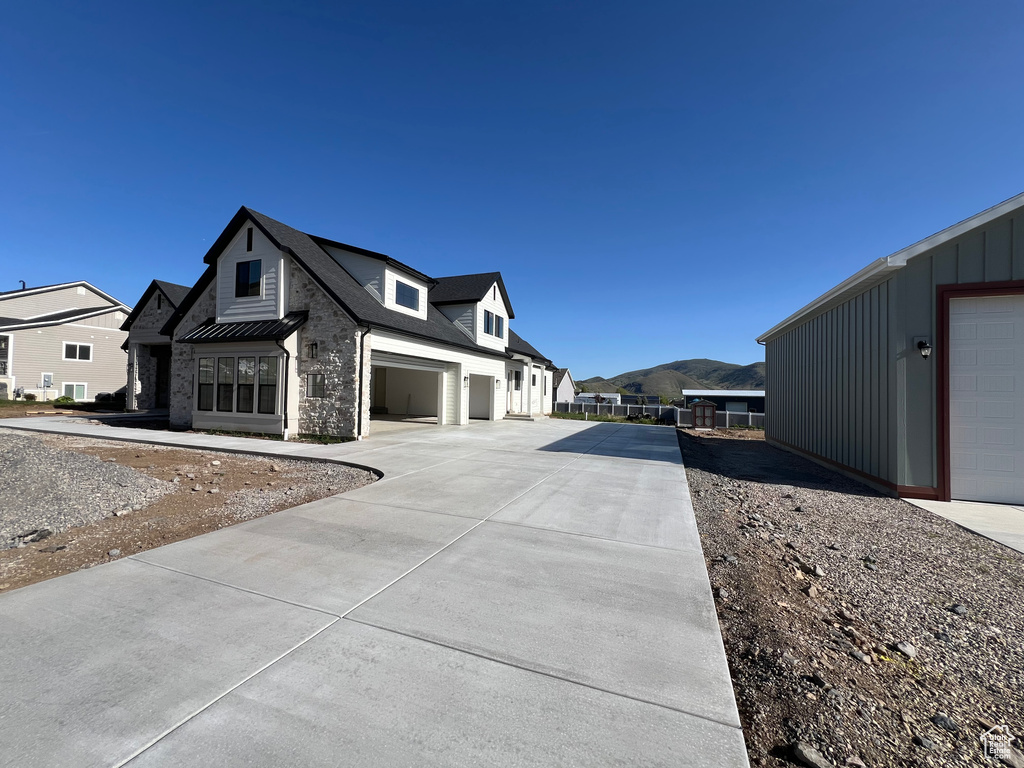 View of side of property featuring board and batten siding, concrete driveway, a standing seam roof, and a residential view