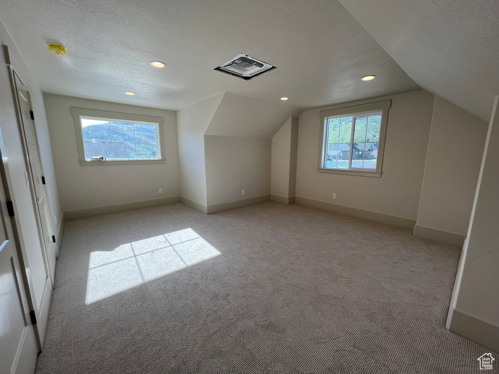 Bonus room featuring light colored carpet, vaulted ceiling, recessed lighting, baseboards, and a textured ceiling