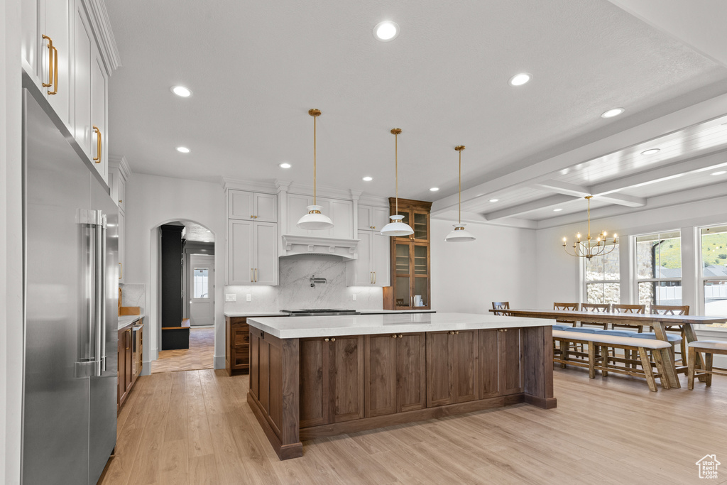 Kitchen with stainless steel appliances, arched walkways, recessed lighting, light countertops, and a spacious island