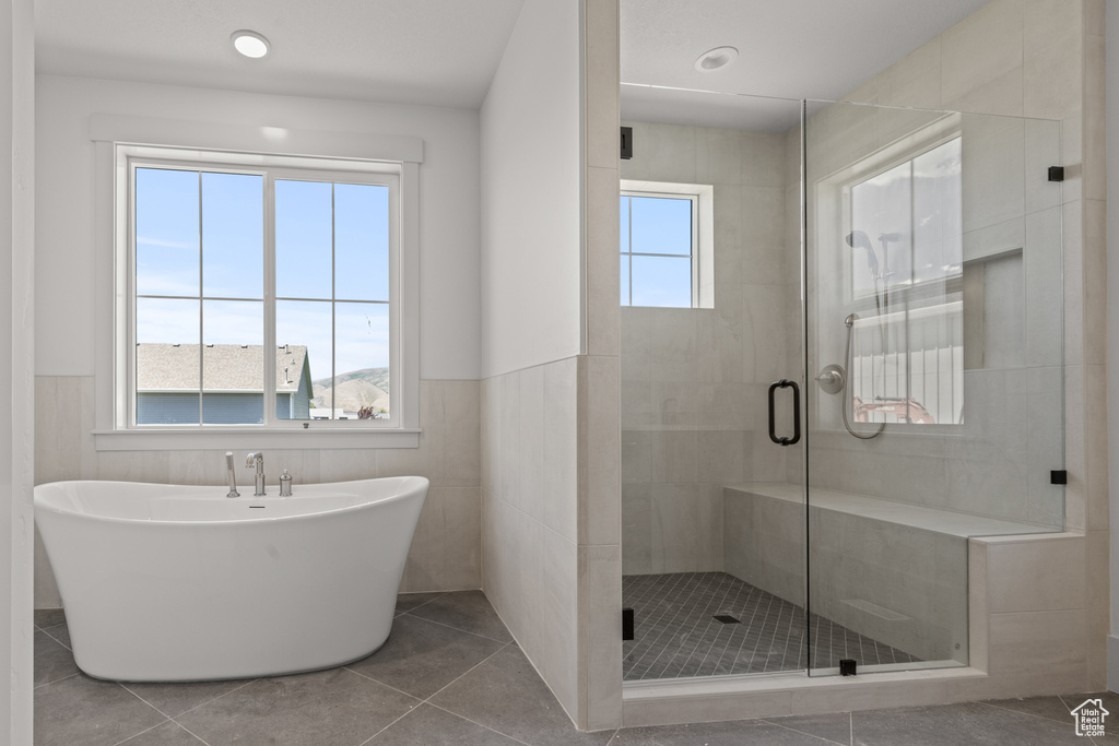 Bathroom with a stall shower, a soaking tub, a wainscoted wall, and tile patterned flooring