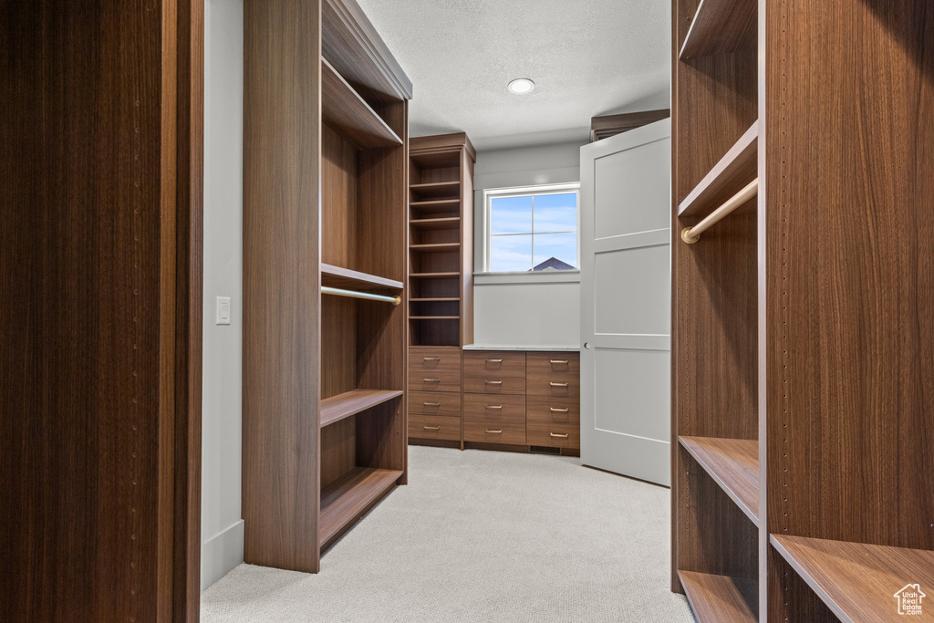 Walk in closet featuring light colored carpet