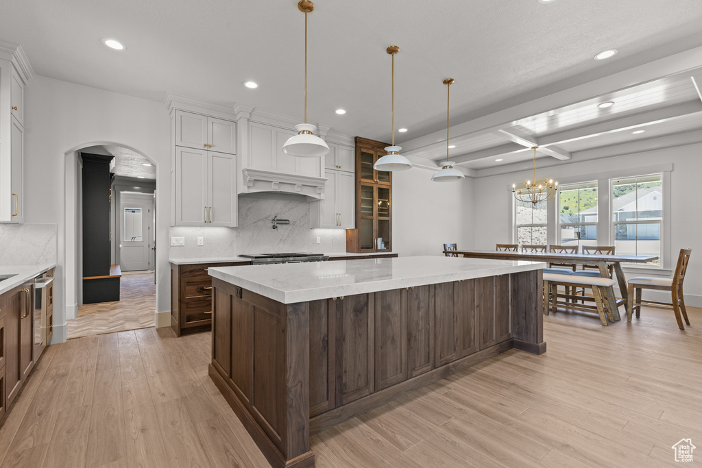 Kitchen with a large island, recessed lighting, backsplash, arched walkways, and light wood finished floors