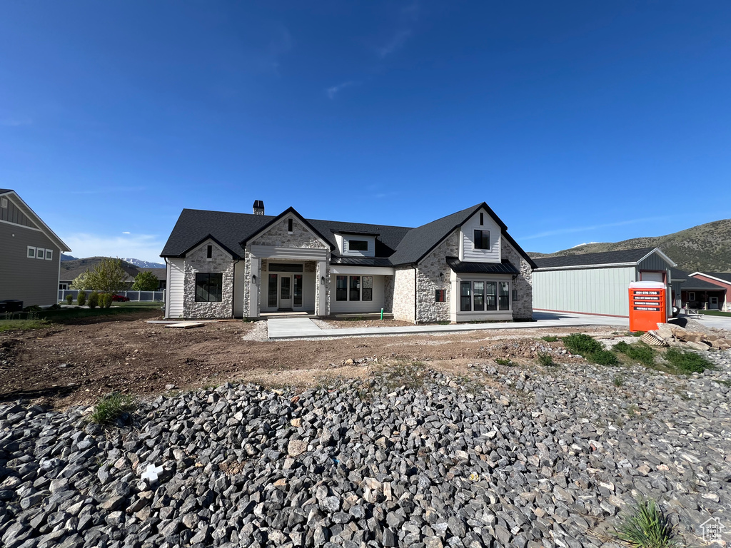 View of front of house with stone siding, french doors, a mountain view, and a chimney