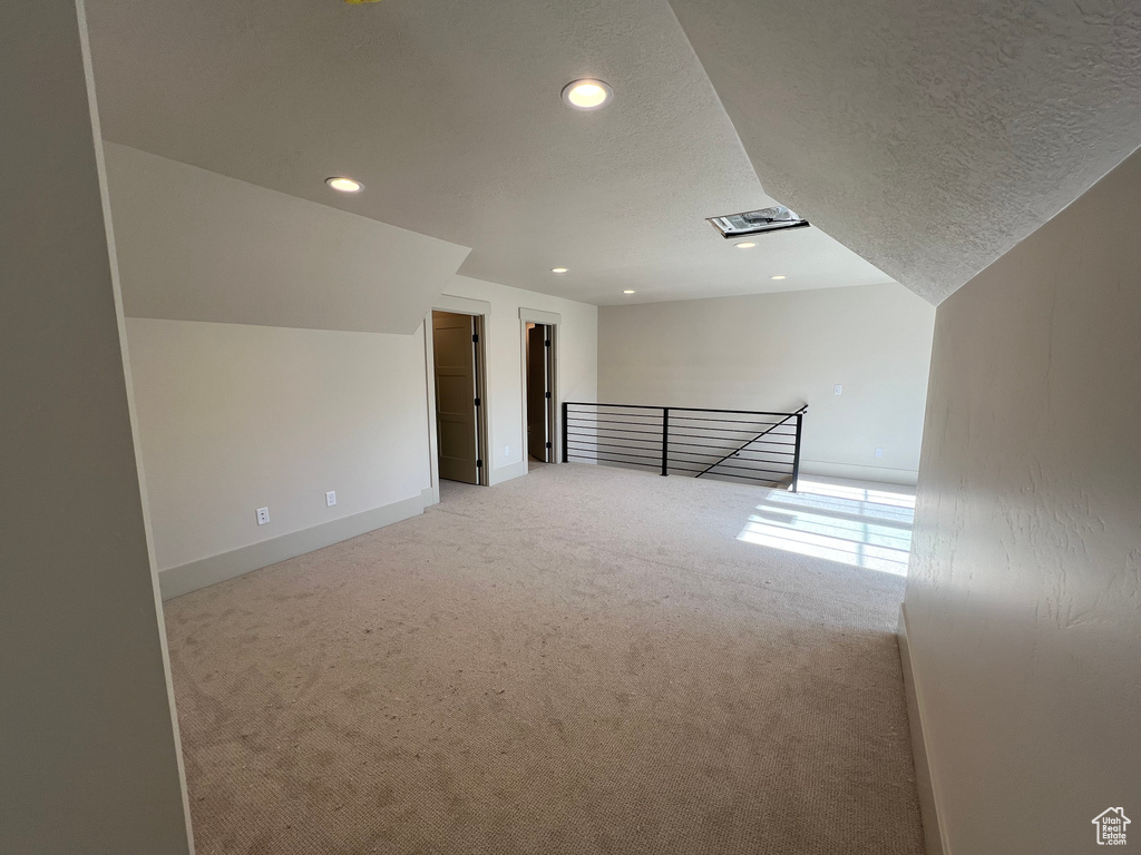 Additional living space featuring light carpet, recessed lighting, a textured ceiling, and baseboards