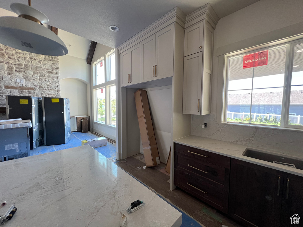 Kitchen with wood finished floors, light stone countertops, tasteful backsplash, and vaulted ceiling