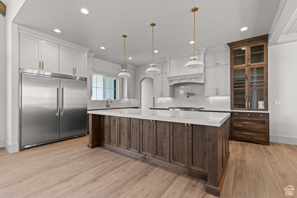 Kitchen featuring built in fridge, backsplash, light wood-style floors, recessed lighting, and a spacious island