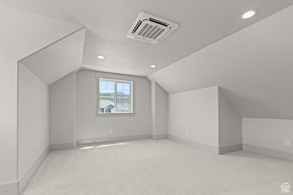Bonus room featuring a textured ceiling, lofted ceiling, carpet, and recessed lighting