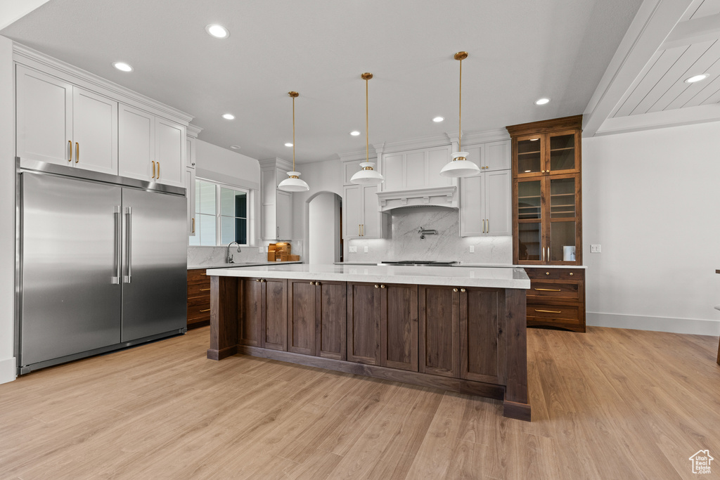 Kitchen with built in fridge, tasteful backsplash, light countertops, recessed lighting, and light wood-type flooring