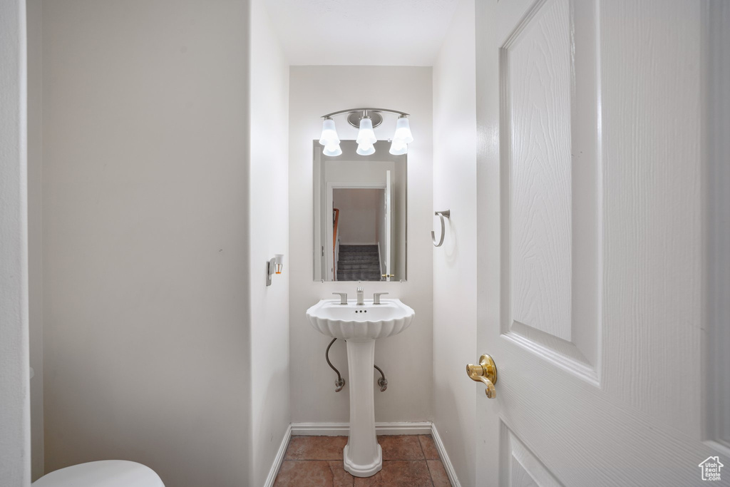 Half bathroom featuring toilet, tile patterned floors, and baseboards