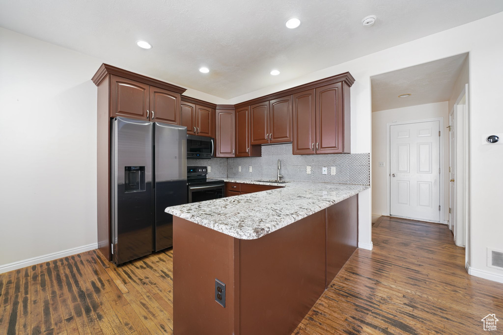 Kitchen featuring stainless steel refrigerator with ice dispenser, a sink, a peninsula, electric stove, and wood finished floors
