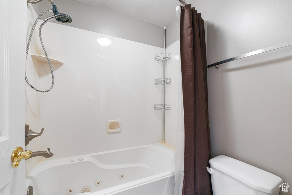 Bathroom featuring toilet and a combined bath / shower with jetted tub