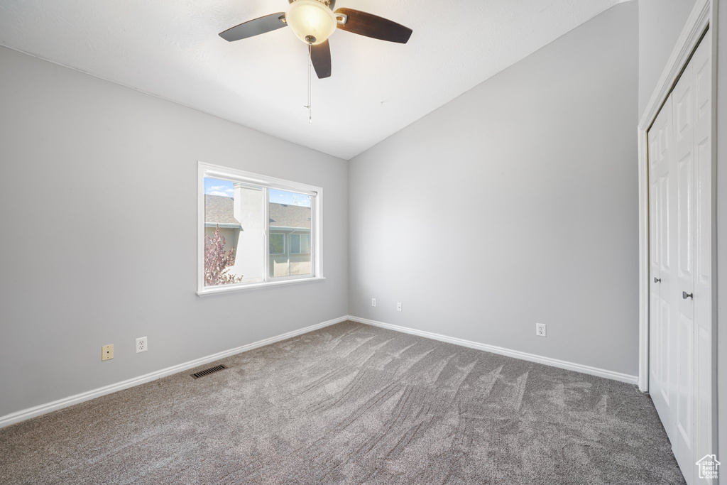 Unfurnished bedroom with baseboards, a closet, vaulted ceiling, and carpet floors