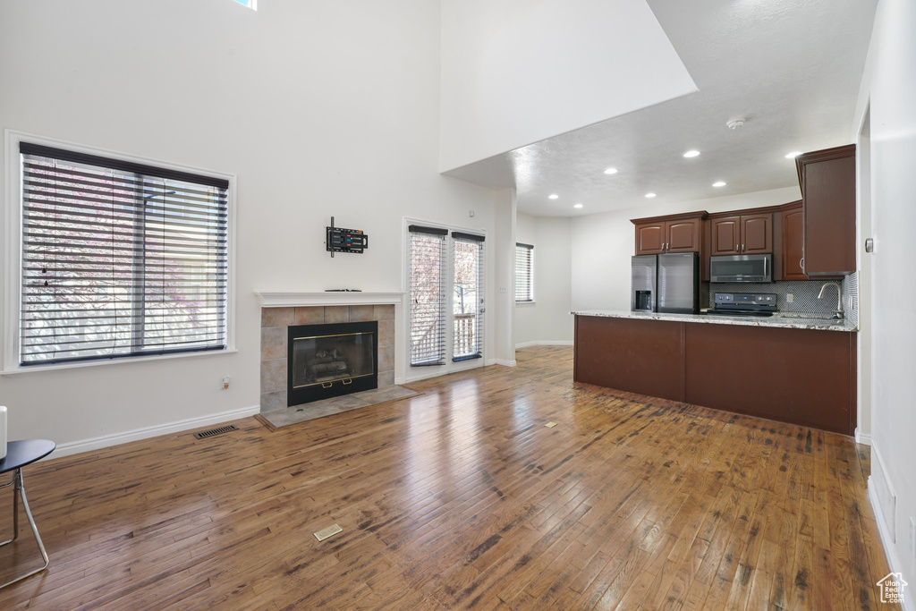 Kitchen featuring baseboards, a peninsula, light wood-style flooring, open floor plan, and appliances with stainless steel finishes
