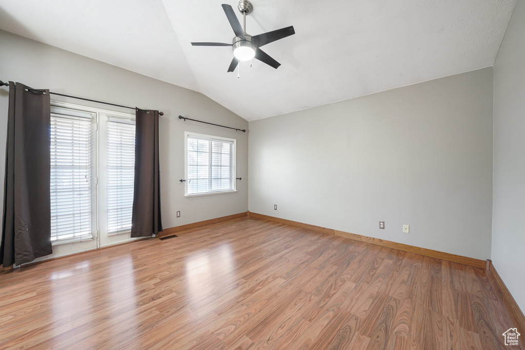 Empty room featuring visible vents, baseboards, a ceiling fan, light wood finished floors, and vaulted ceiling