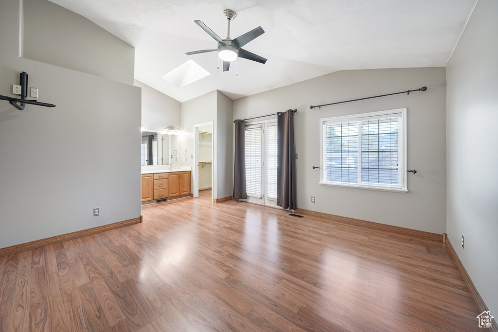 Unfurnished living room featuring light wood-style floors, a ceiling fan, visible vents, and lofted ceiling with skylight