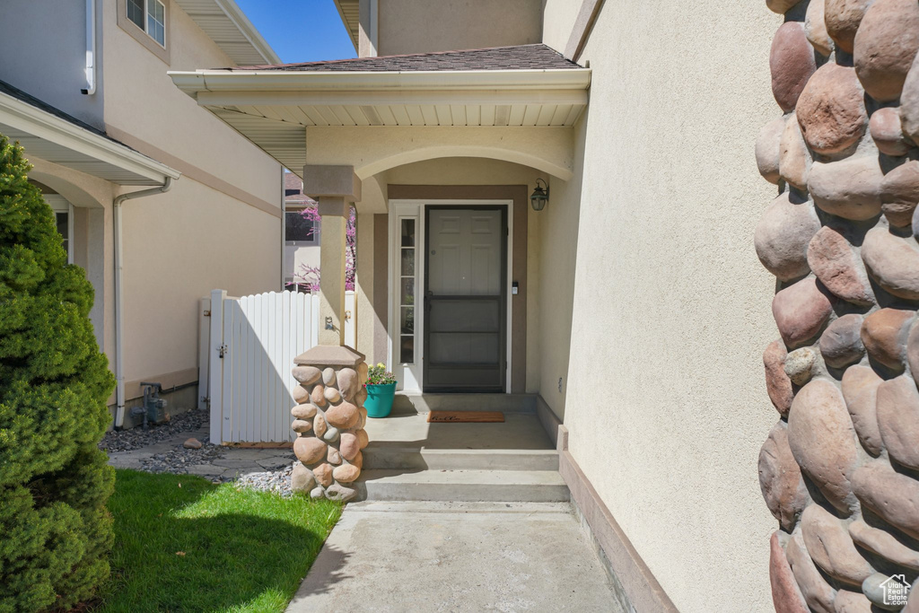 View of exterior entry with stucco siding, fence, and a gate