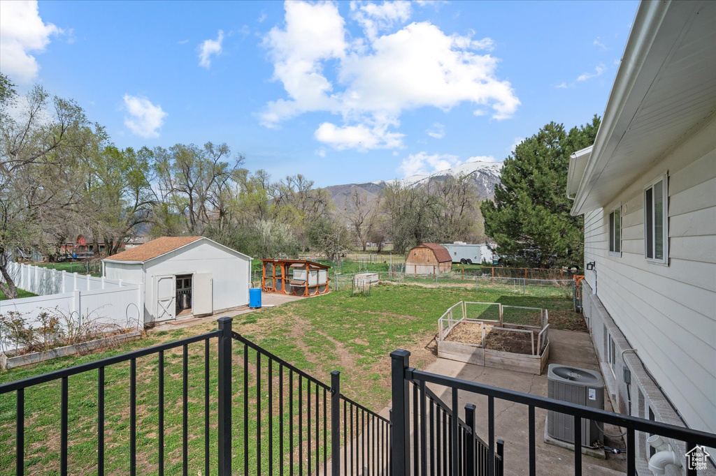 View of yard featuring central AC, a garden, a mountain view, a storage shed, and an outbuilding