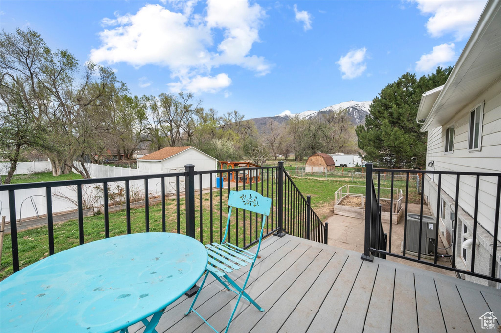 Deck featuring outdoor dining space, an outdoor structure, a mountain view, a yard, and fence