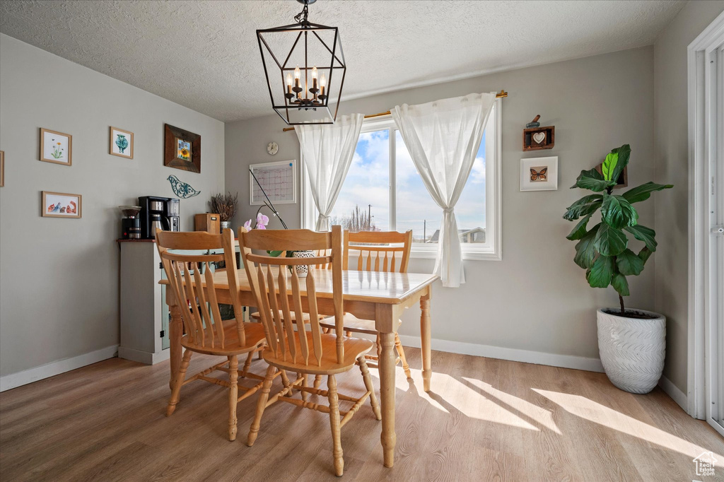 Dining space with baseboards, a notable chandelier, and wood finished floors