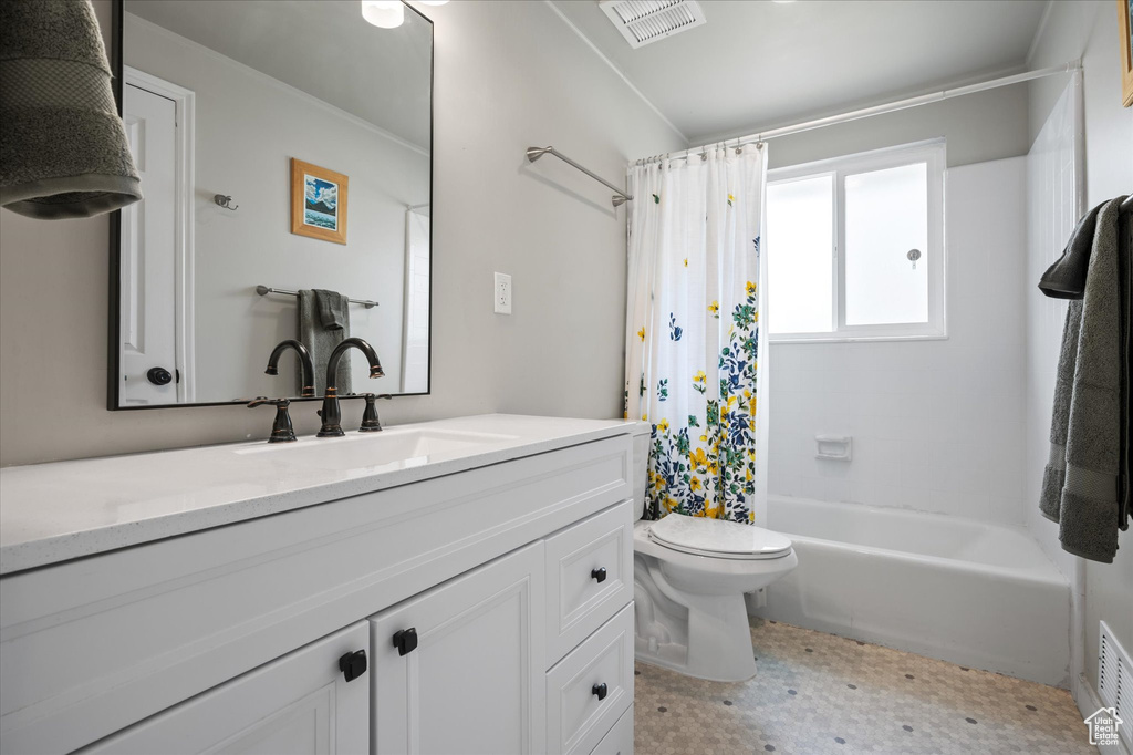 Bathroom featuring toilet, vanity, shower / tub combo with curtain, and visible vents