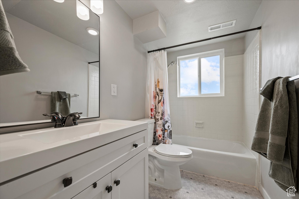 Bathroom with visible vents, toilet, vanity, and shower / bath combination with curtain