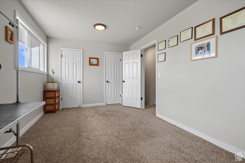 Unfurnished bedroom with carpet, baseboards, and multiple closets