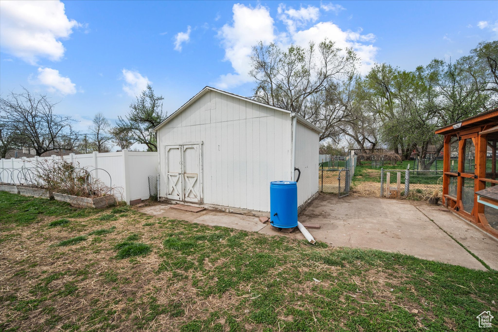View of outbuilding with a gate, fence, an outbuilding, and a vegetable garden