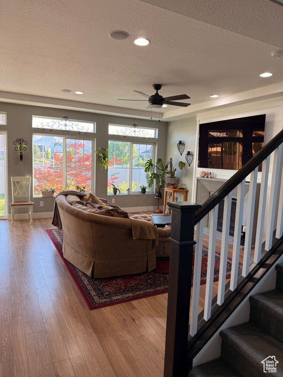 Living area with a textured ceiling, wood finished floors, baseboards, stairway, and recessed lighting