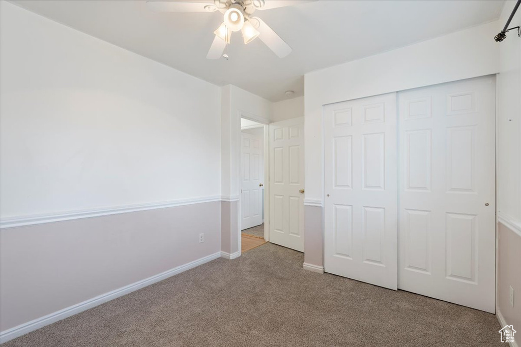 Unfurnished bedroom with carpet, a closet, baseboards, and ceiling fan