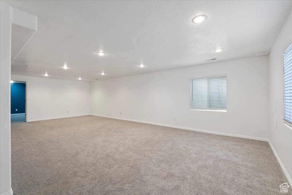 Carpeted empty room featuring visible vents, baseboards, recessed lighting, and a wealth of natural light