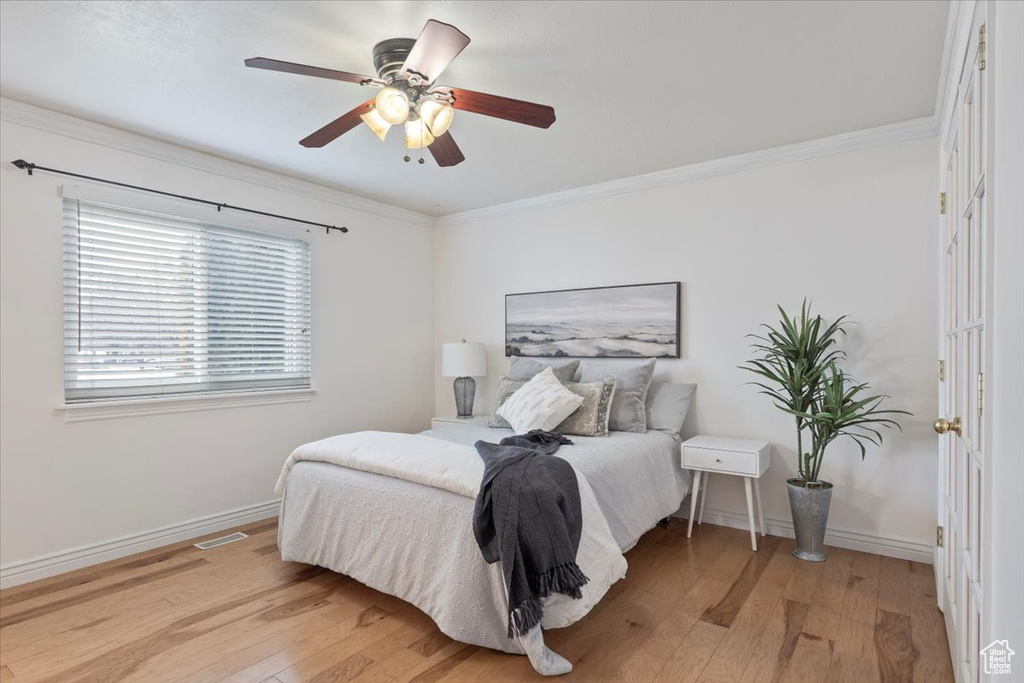 Bedroom with light wood-type flooring, crown molding, and baseboards