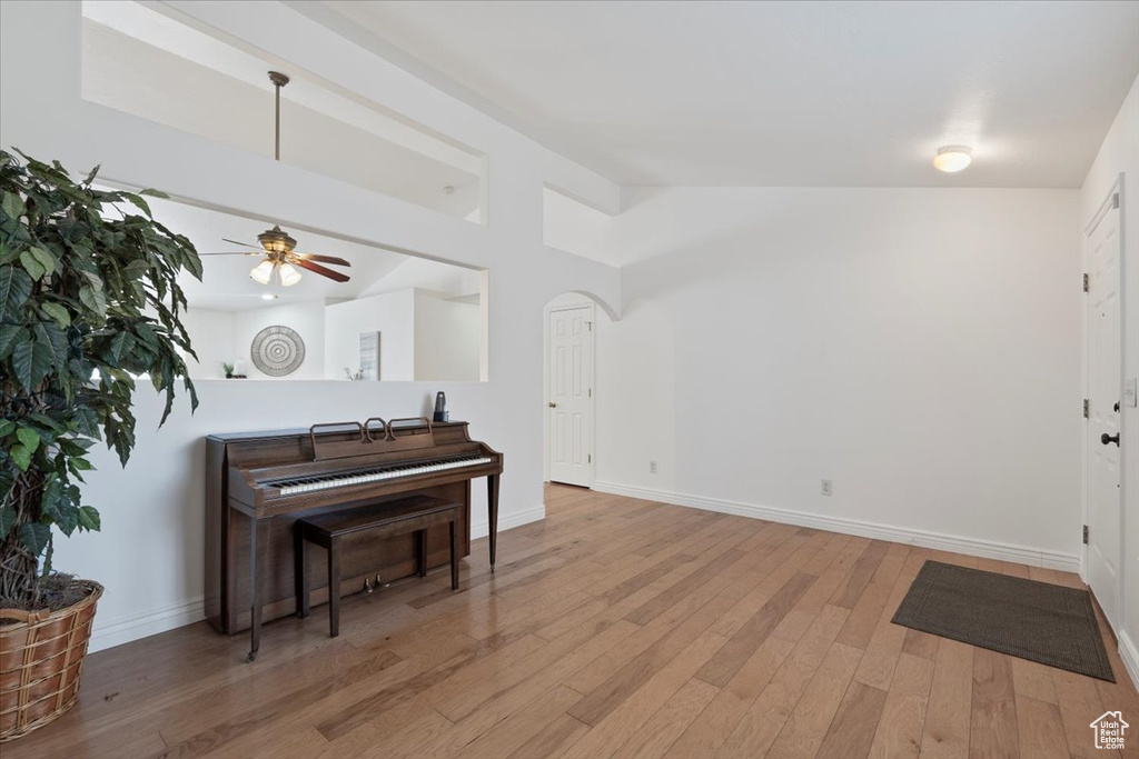 Interior space featuring arched walkways, wood finished floors, baseboards, and a ceiling fan
