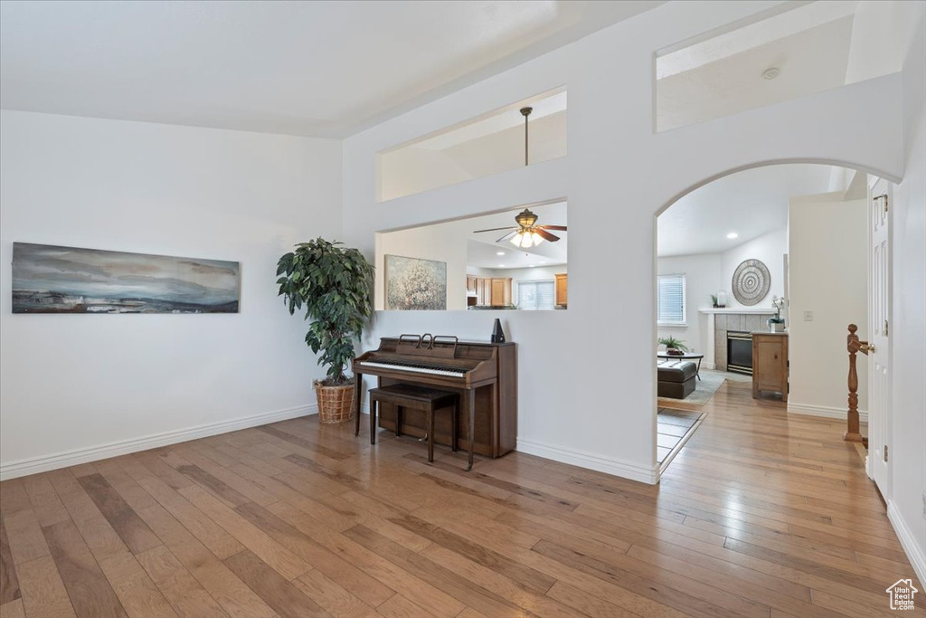 Living area with baseboards, arched walkways, ceiling fan, a fireplace, and wood-type flooring