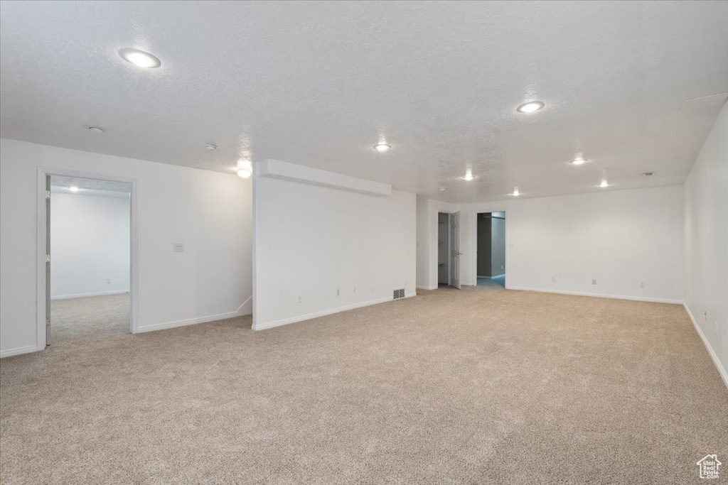 Finished below grade area featuring light colored carpet, baseboards, and recessed lighting