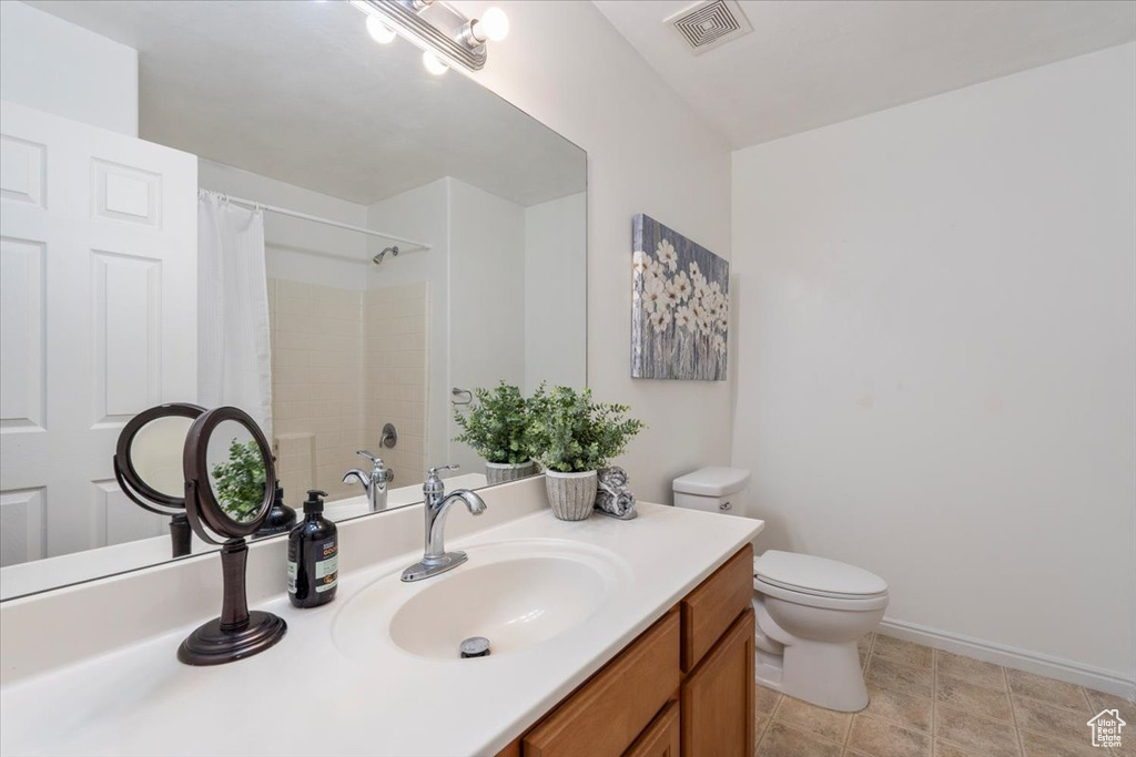 Bathroom with visible vents, baseboards, curtained shower, toilet, and vanity