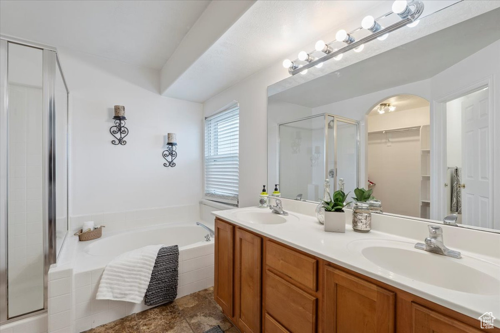 Bathroom featuring double vanity, a stall shower, a walk in closet, a bath, and a sink
