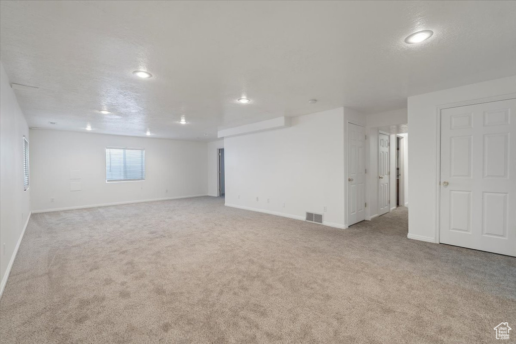 Carpeted empty room featuring baseboards, visible vents, and recessed lighting