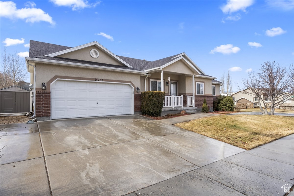 Single story home with brick siding, a porch, driveway, and stucco siding