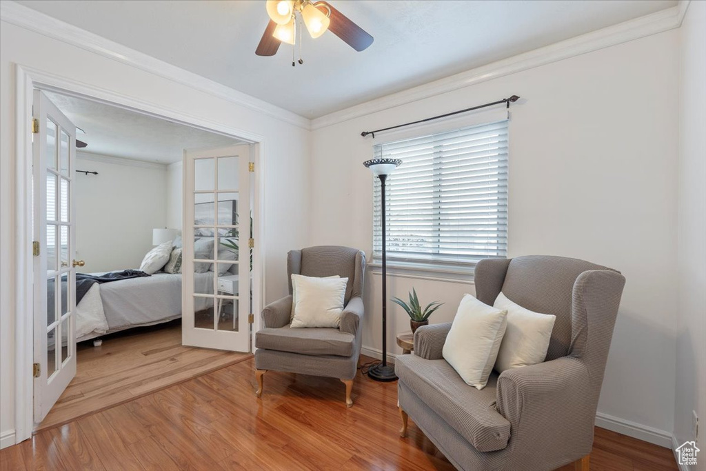 Living area with crown molding, ceiling fan, a wealth of natural light, and wood finished floors