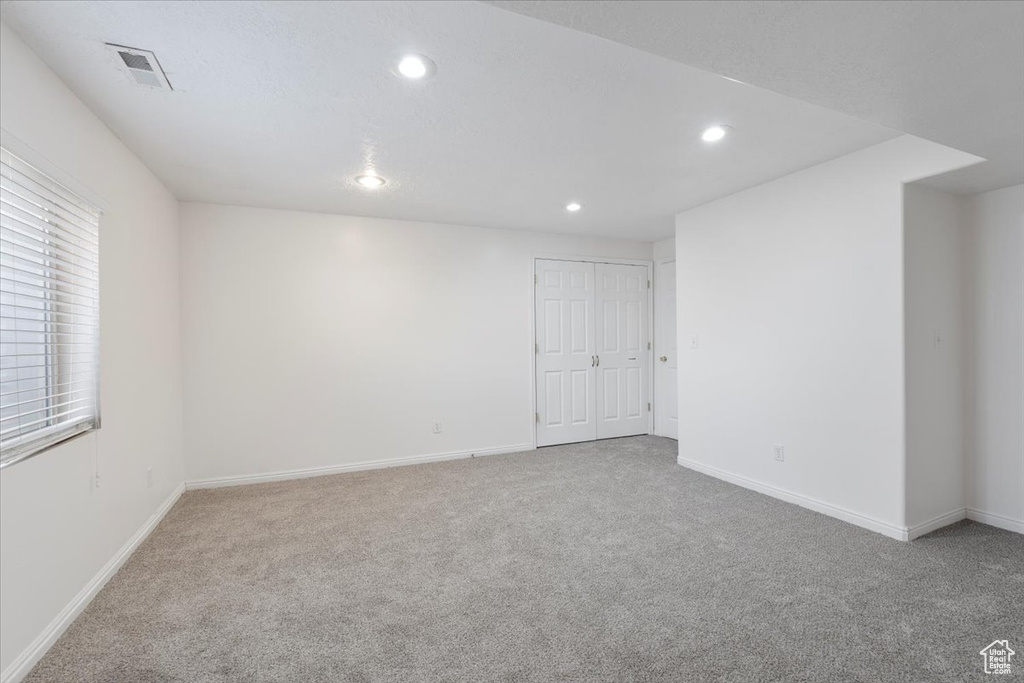 Carpeted empty room featuring baseboards, visible vents, and recessed lighting