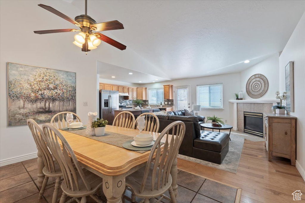 Dining space featuring baseboards, a tiled fireplace, ceiling fan, recessed lighting, and vaulted ceiling