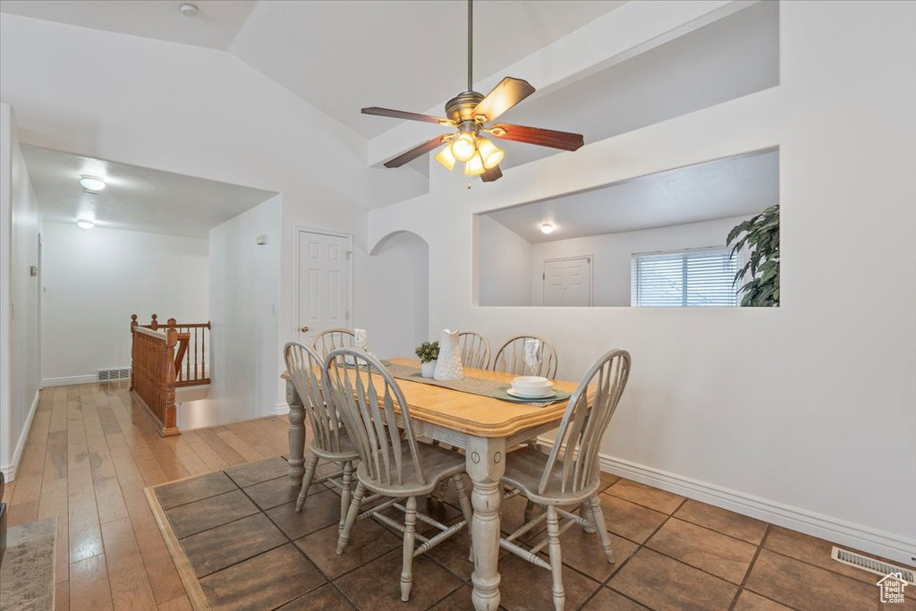 Dining area featuring baseboards, a ceiling fan, hardwood / wood-style floors, high vaulted ceiling, and arched walkways